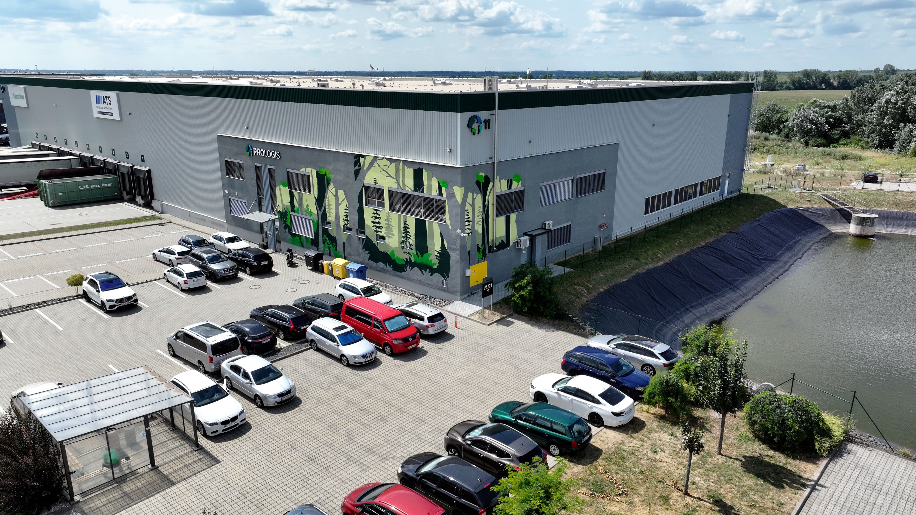 Mural at Prologis Park Bratislava warehouse building with mural on facade, parking lot nearby