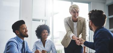 Office workers with a woman and man shaking hands at a table