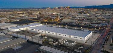 Aerial view of Prologis Vernon Business Center with Prologis globe logo on corner of building, located in Los Angeles, California with LA in city skyline in the distance.
