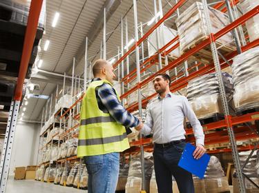Two people shaking hands in a warehouse