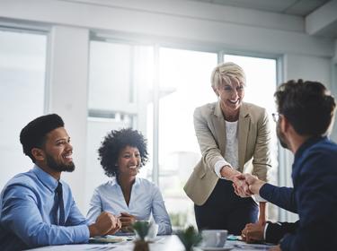 Office workers with a woman and man shaking hands at a table