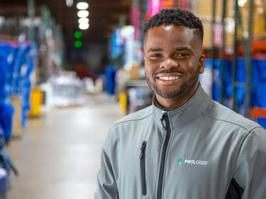 Prologis maintance tech, Max Igwe, wearing Prologis branded jacket posing in warehouse in California