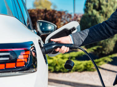 Egy személy, aki tölti az elektromos járművét