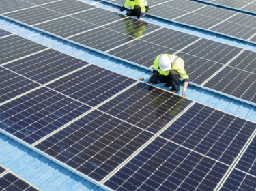 Workers installing solar panels on a roof
