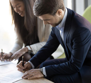 Two people signing paperwork Two people signing paperwork