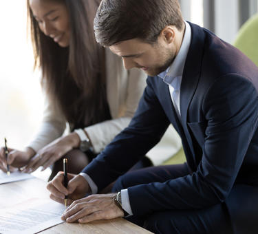 Two people signing paperwork