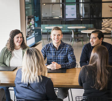 Six team members sit at a table in the Denver office 