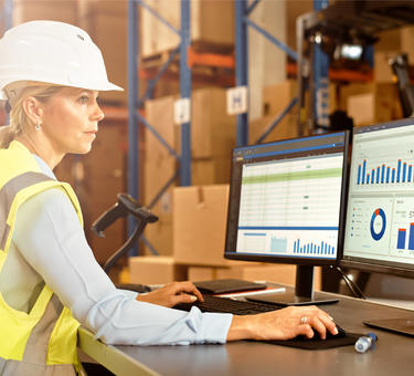 A woman in a warehouse working with fleet management software A woman in a warehouse working with fleet management software