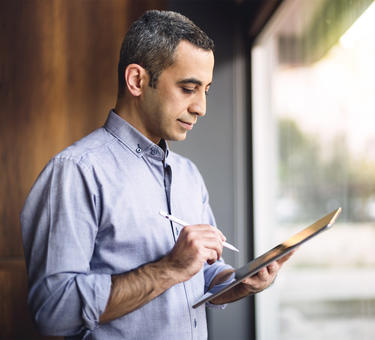 A man uses a stylus to review data on a tablet