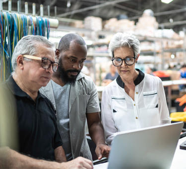 Three people looking at a laptop