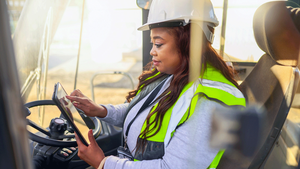essentials-operations-right.jpg Woman driving a forklift in a white hard hat and safety vest