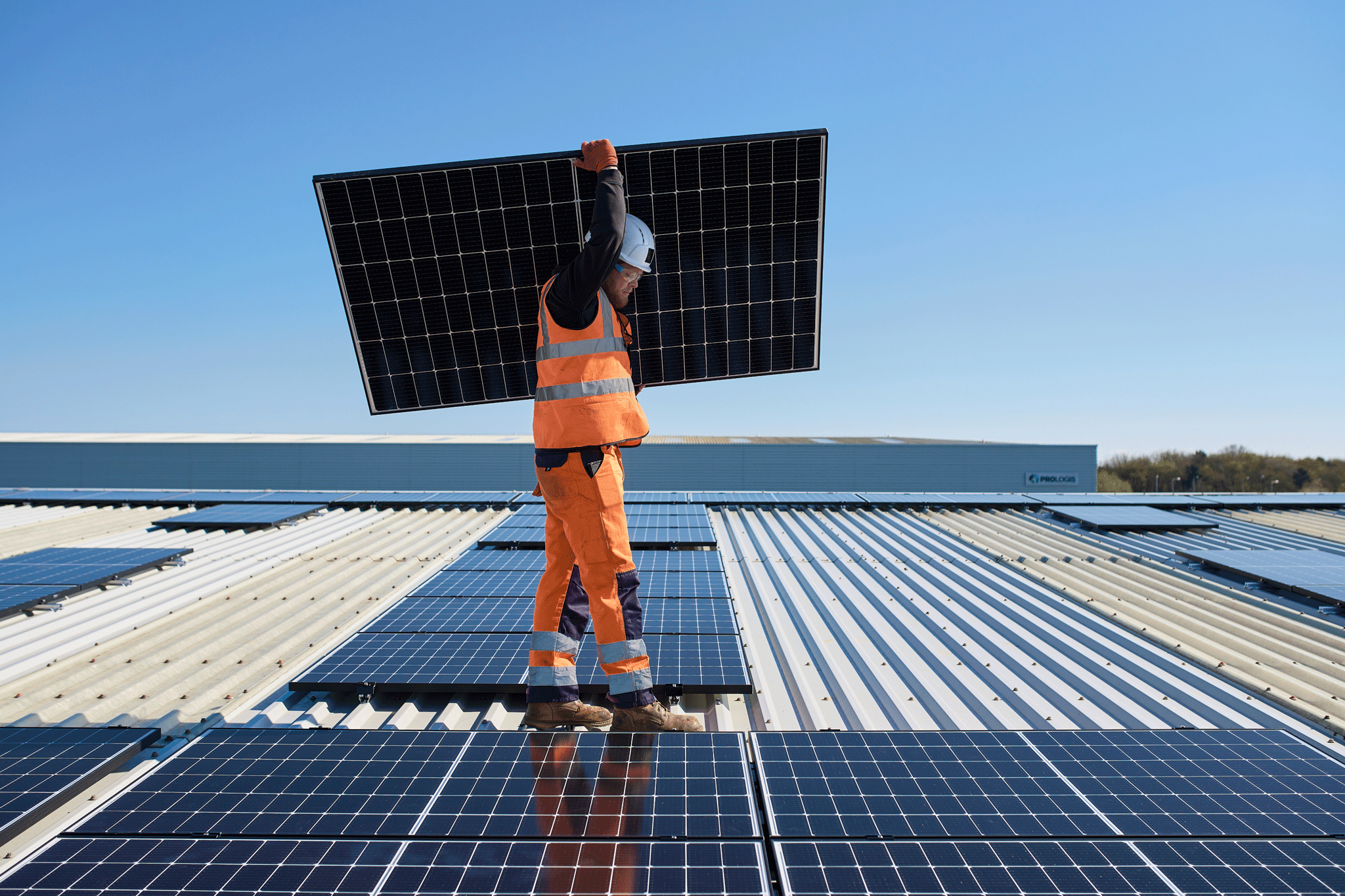 Person carrying a solar panel on a roof Person carrying a solar panel on a roof